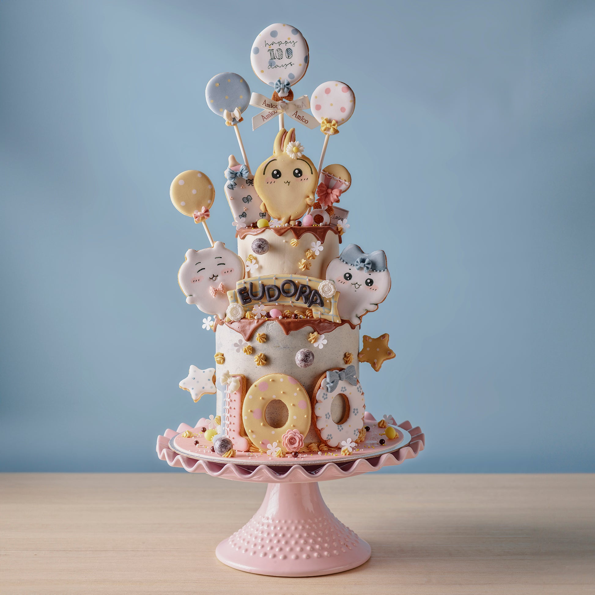 Amico 百日宴客製化蛋糕，搭配可愛卡通造型與氣球糖霜裝飾，為嬰兒100日慶祝增添甜蜜氣氛。