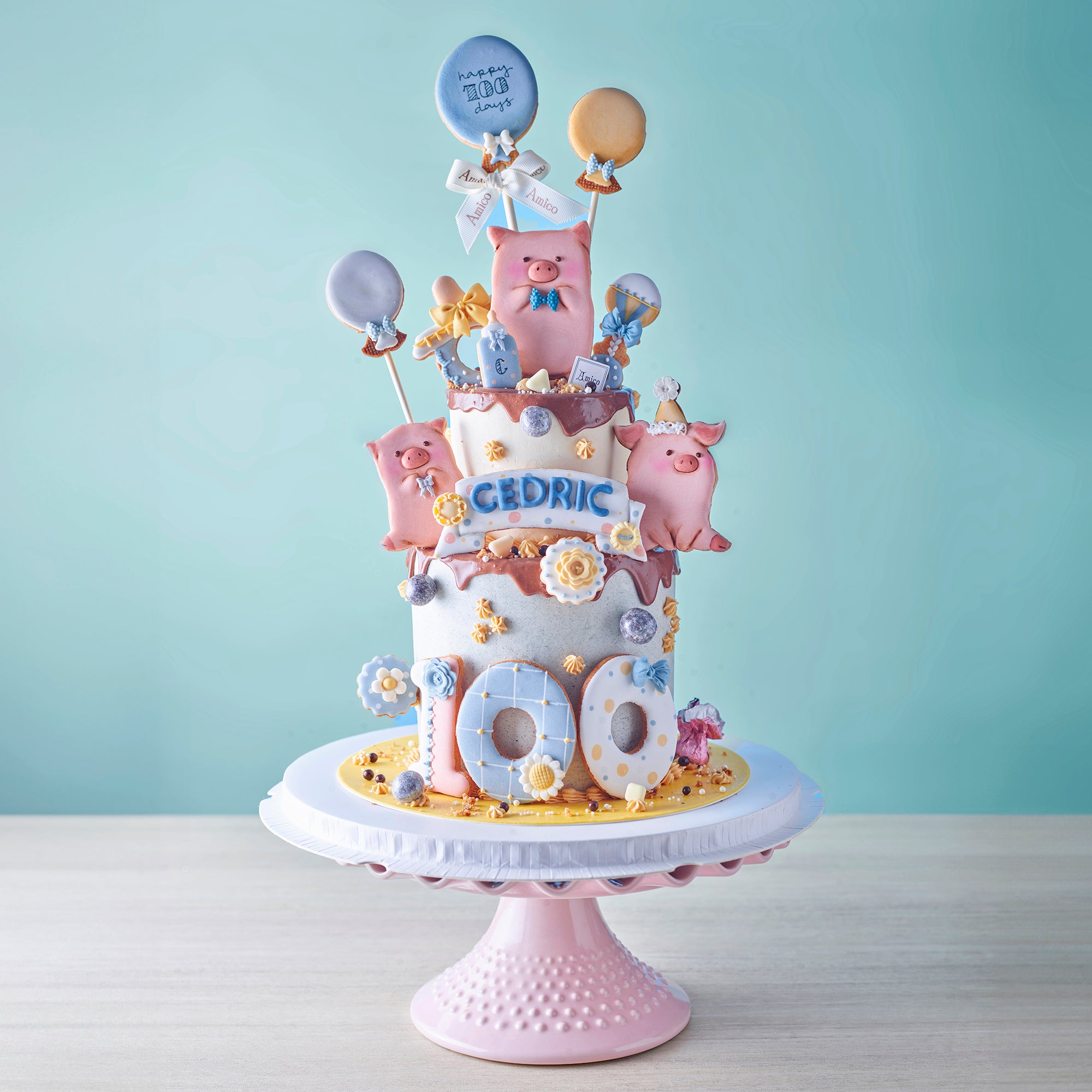 Amico LuLu 豬主題百日宴蛋糕，以可愛卡通小豬與氣球糖霜裝飾，慶祝寶寶 100 天特別時刻