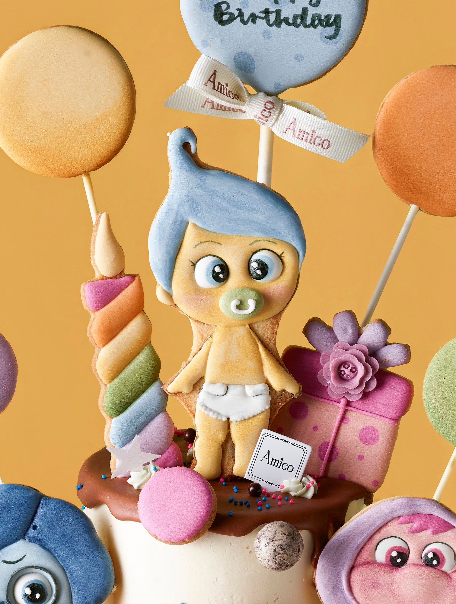 Amico Pasticceria 訂製《玩轉腦朋友》(Inside Out) 嬰兒主題大型派對套餐，專為一歲生日設計。包含一個以 BB 版阿愁 (Sadness)、阿樂 (Joy) 等角色及氣球裝飾的雙層專屬生日蛋糕，並搭配同主題的精緻杯子蛋糕，以及彩虹、奶瓶、嬰兒包屁衣造型的手工糖霜曲奇。